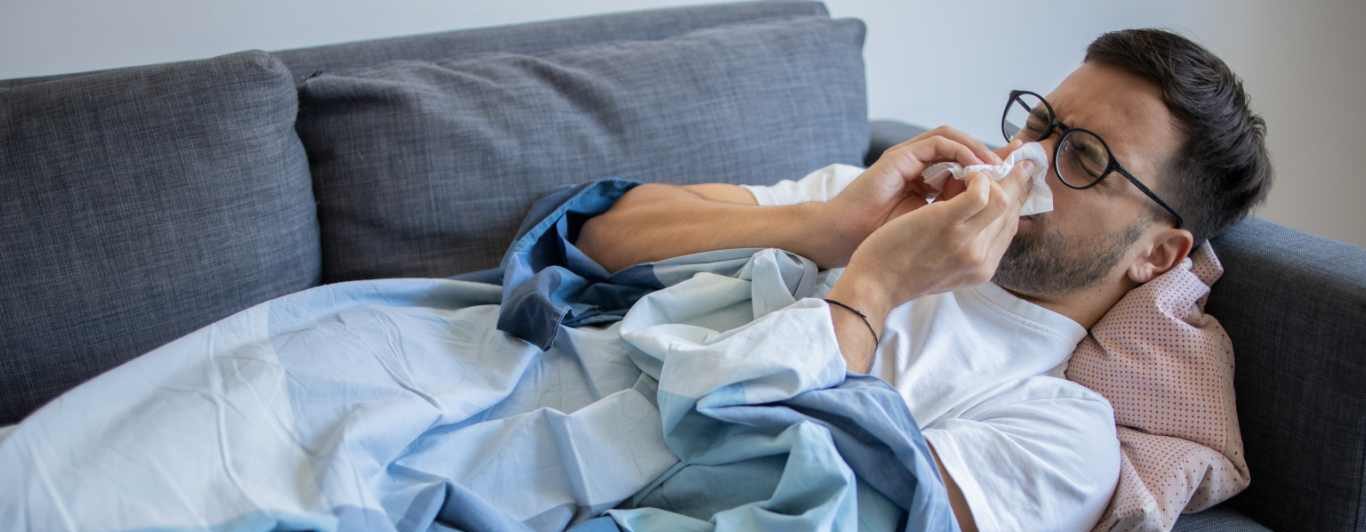 Man blowing nose with COVID-19 symptoms