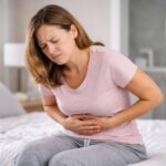 Woman holding their gut with abdominal pain.